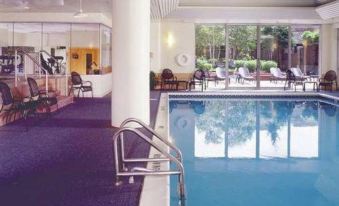 an indoor swimming pool surrounded by a gym , with several people exercising in the area at UMass Lowell Inn and Conference Center