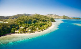 aerial view of a tropical island surrounded by clear blue water , surrounded by lush green vegetation at Malolo Island Resort