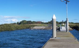 a calm river with a white column on the right side and a light post next to it at Toora Lodge Motel