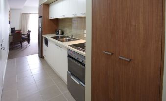 a kitchen with wooden cabinets , a stainless steel oven and sink , and an open cabinet at Quest Mildura