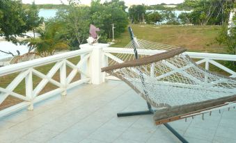 a hammock is hanging on a white railing , with a view of trees and water in the background at Cottage Cut Villas