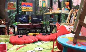 a living room with a gaming setup , including two tvs , a chair , and a bed at Amaroossa Hotel Bandung Indonesia