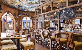 a modern bar with wooden furniture , a tv screen , and various liquor bottles on the shelves , under a ceiling adorned with maps at Hyatt Regency Huntington Beach Resort and Spa