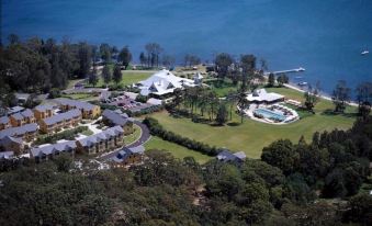 aerial view of a large resort with multiple buildings , including a conference center , and a lake in the background at BreakFree Raffertys Beach Resort