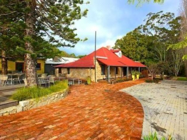 a brick house with a red roof is surrounded by trees and a brick patio at Inn Mahogany Creek