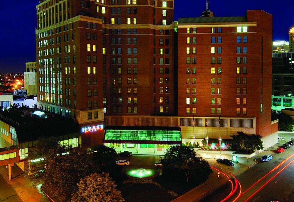 a large hotel with a red sign and multiple floors , lit up at night against the backdrop of a busy city street at Hyatt Regency Buffalo Hotel and Conference Center