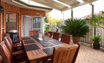 a wooden dining table surrounded by chairs , situated on a patio with a brick wall and potted plants at Durham Lodge Bed & Breakfast