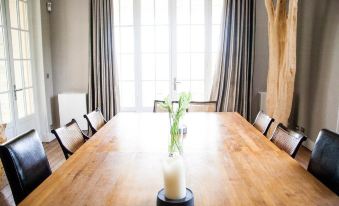 a dining room with a wooden dining table surrounded by chairs , and a vase of flowers placed on the table at Villa la Tosca