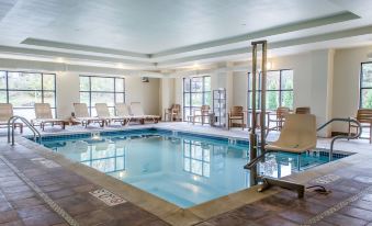 a large indoor swimming pool with lounge chairs and tables , surrounded by windows that allow natural light to enter at Comfort Suites Lewisburg