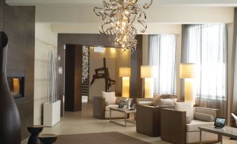 a modern living room with a chandelier , large windows , and comfortable seating arrangements under the same design at Estérel Resort