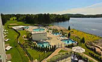 an aerial view of a large outdoor swimming pool area with multiple buildings , surrounded by trees and water at Estérel Resort