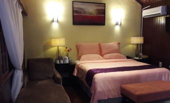 a cozy bedroom with a pink bedspread , two lamps on the wall , and a couch at Shah's Beach Resort