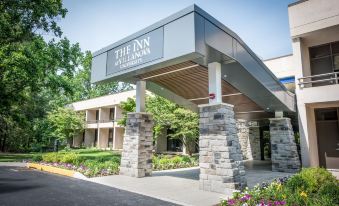 an exterior view of a hotel with a large sign above the entrance and stone pillars at Inn at Villanova University