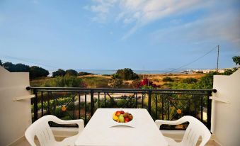 a white dining table with chairs on a balcony overlooking the ocean , creating a serene atmosphere at Sea View Hotel & Apartments