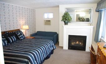 a bedroom with a bed , blue and white striped blanket , a couch , and a fireplace at Christman's Windham House