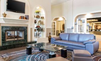a modern living room with a blue leather couch , a glass coffee table , and a fireplace at Quality Inn Festus