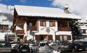 "a large , white building with a sign that says "" hotel suizo "" is surrounded by parked cars and snow" at Santa San