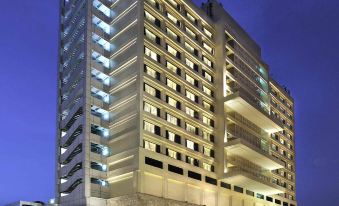 a modern building with multiple floors , surrounded by trees and buildings , illuminated at night at Crowne Plaza New Delhi Mayur Vihar Noida