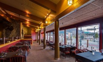 a restaurant with wooden tables and chairs , large windows , and hanging lights , offering a view of the city at Westmark Sitka