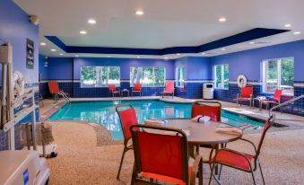 a large indoor swimming pool surrounded by chairs and tables , with people enjoying their time in the pool area at Homewood Suites by Hilton Dover
