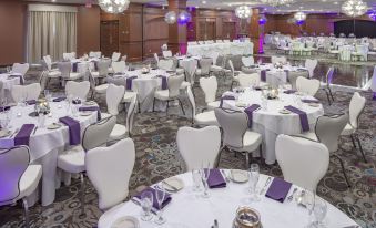 a large banquet hall filled with white and purple tables , chairs , and chandeliers , creating an elegant atmosphere at Ashworth by the Sea