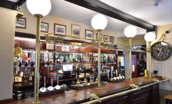 a well - lit bar with various bottles and glasses , as well as a cash register in the background at The George Hotel