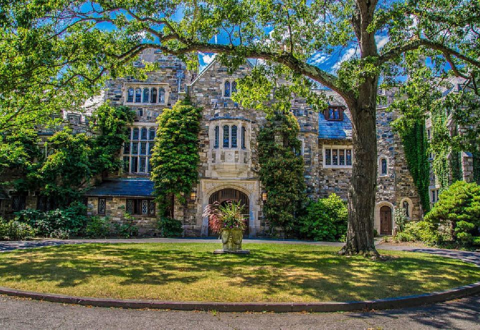 a large stone building with a tree in front of it , surrounded by grass and trees at The Castle at Skylands Manor