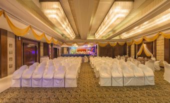 a large banquet hall with rows of white chairs arranged for a formal event , possibly a wedding reception at The Regenza by Tunga