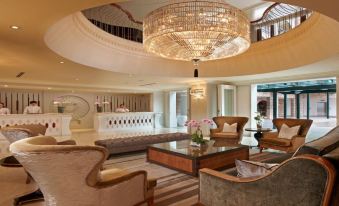 a luxurious hotel lobby with two couches , a coffee table , and a large chandelier hanging from the ceiling at The Chateau Spa & Wellness Resort