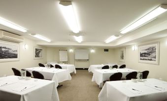 a conference room set up for a meeting , with tables and chairs arranged in a semicircle at Coogee Sands Hotel & Apartments