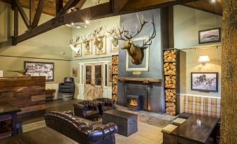 a living room with a fireplace , leather couches , and deer heads mounted on the walls at Hanmer Springs Retreat