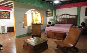 a cozy bedroom with a large bed , wooden furniture , and a variety of paintings on the walls at Hotel La Hacienda