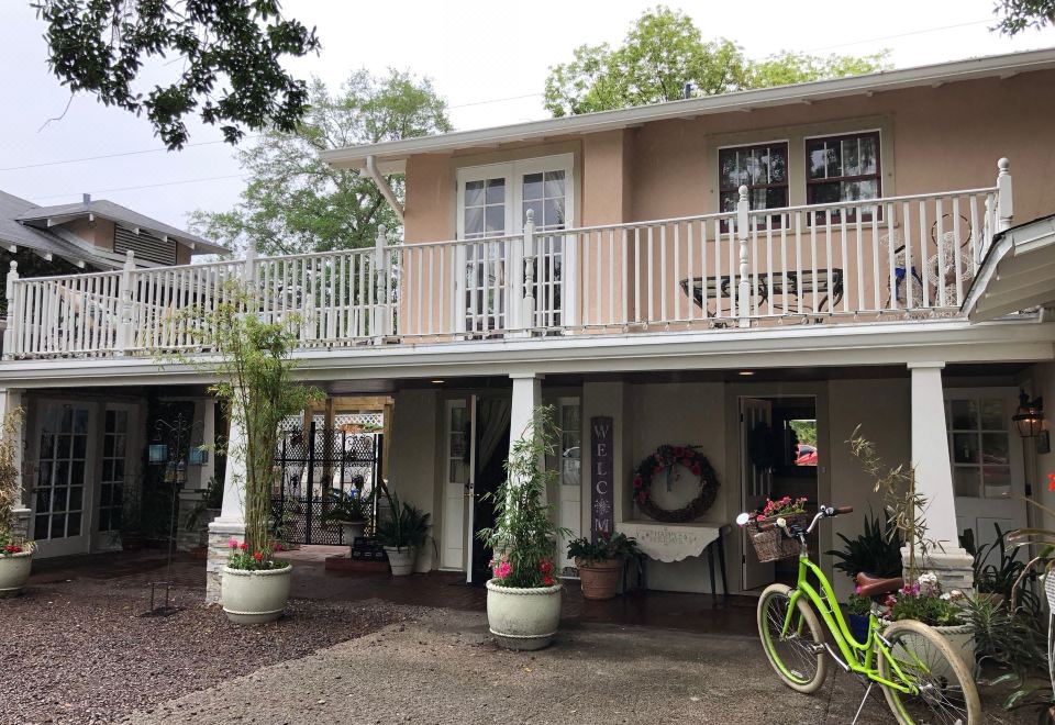 a large house with a balcony and two bikes parked in front of it , surrounded by plants and trees at Park Place Inn and Cottages