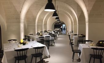 an elegant dining room with white tablecloths and black chairs , creating a warm and inviting atmosphere at Masseria Amastuola Wine Resort