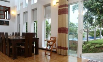 a dining room with a wooden table , chairs , and a chair in the corner near a window at Capital Villa