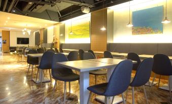 a modern dining area with tables and chairs arranged in rows , creating a clean and inviting atmosphere at Hub Hotel