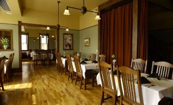 a dining room with wooden floors , tables and chairs arranged for a group of people to enjoy a meal together at Midland Railroad Hotel