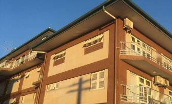 a three - story apartment building with a brown exterior and green trim , under a clear blue sky at Suva Motor Inn