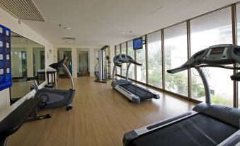 a gym with various exercise equipment , including treadmills and stationary bikes , located in a spacious room with large windows at Impiana Hotel Ipoh