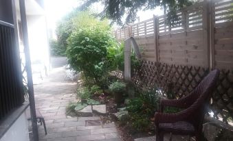 a small backyard with a wooden fence , a chair , and a table , surrounded by greenery at Hotel Bauer