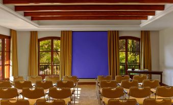 a large room with rows of wooden chairs and a blue screen in the background at Sheraton Mallorca Arabella Golf Hotel