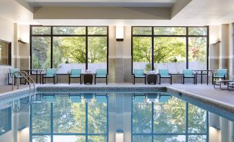 an indoor swimming pool with a large window , surrounded by lounge chairs and trees outside at Residence Inn Bangor