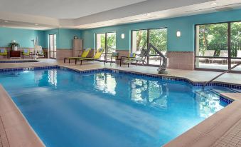 an indoor swimming pool with a large window , surrounded by lounge chairs and tables , in a well - lit room at SpringHill Suites Centreville Chantilly