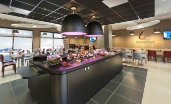 a restaurant with a large black dining table surrounded by chairs , and a buffet table filled with food at ibis Lyon Sud Oullins