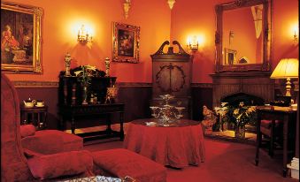 a cozy living room with red walls , gold accents , and a large chandelier hanging from the ceiling at Lumley Castle Hotel