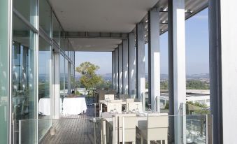 a modern restaurant with white chairs and tables , large windows , and a view of the outdoors at Hotel Horizon