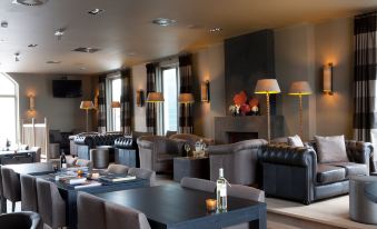 a modern restaurant with gray and black couches , black dining tables , and yellow floor lamps at Fletcher Hotel - Restaurant Nautisch Kwartier