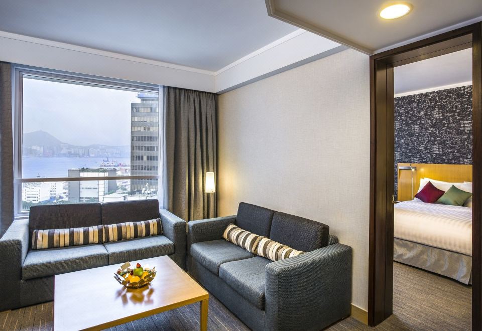 The living room features large windows and furniture, including couches positioned to face the front window at Novotel Century Hong Kong