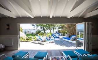 a patio with blue lounge chairs and a large window overlooking a body of water at Harbour Hotel & Spa Christchurch