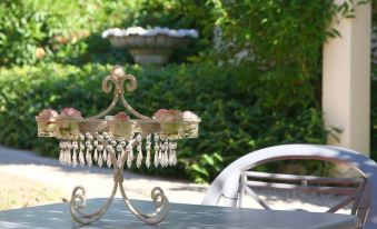 a metal chandelier is on a table in an outdoor setting with chairs and trees at Le Continental